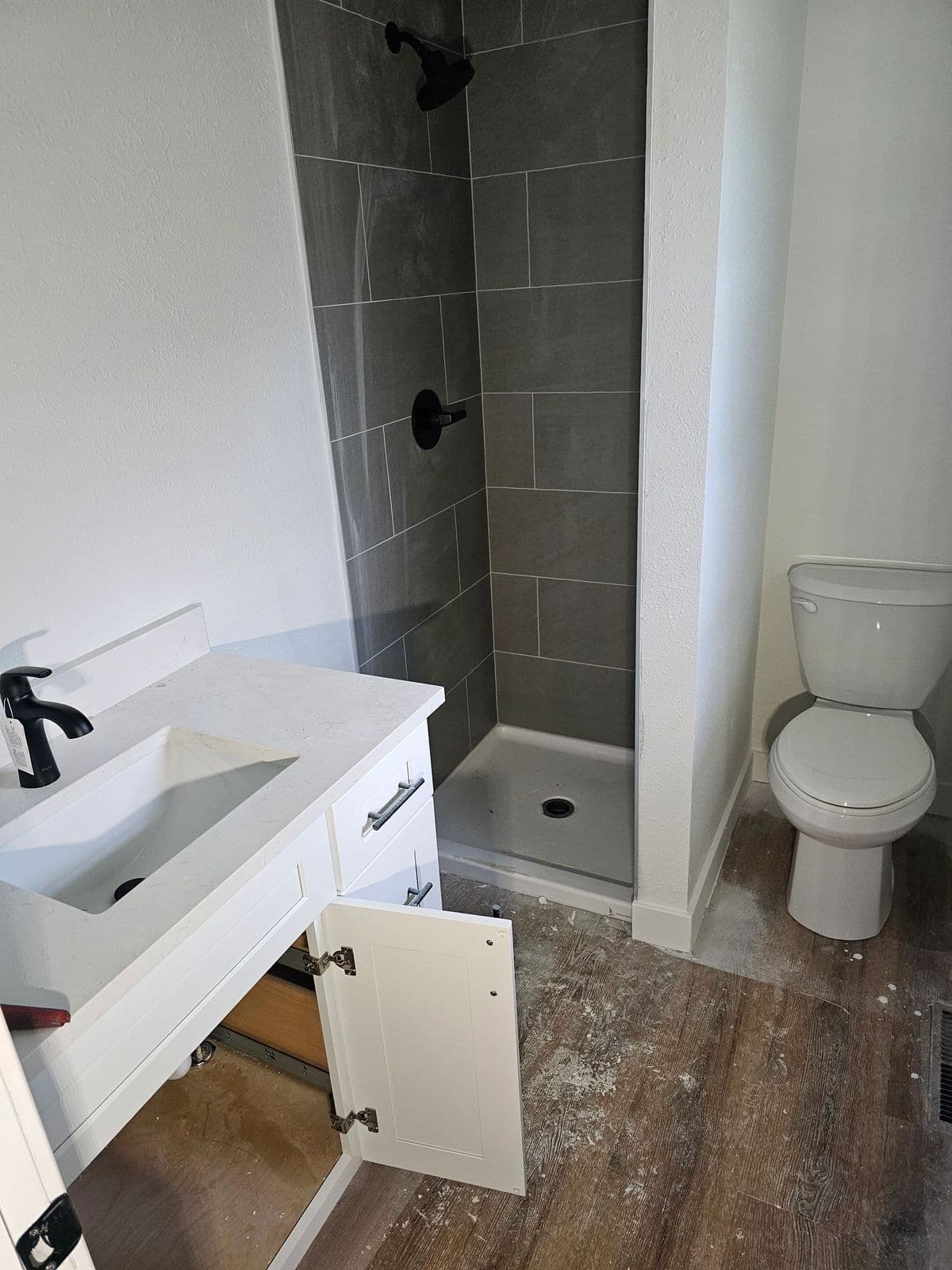 Bathroom vanity, walk-in shower, and toilet after a residential plumbing install